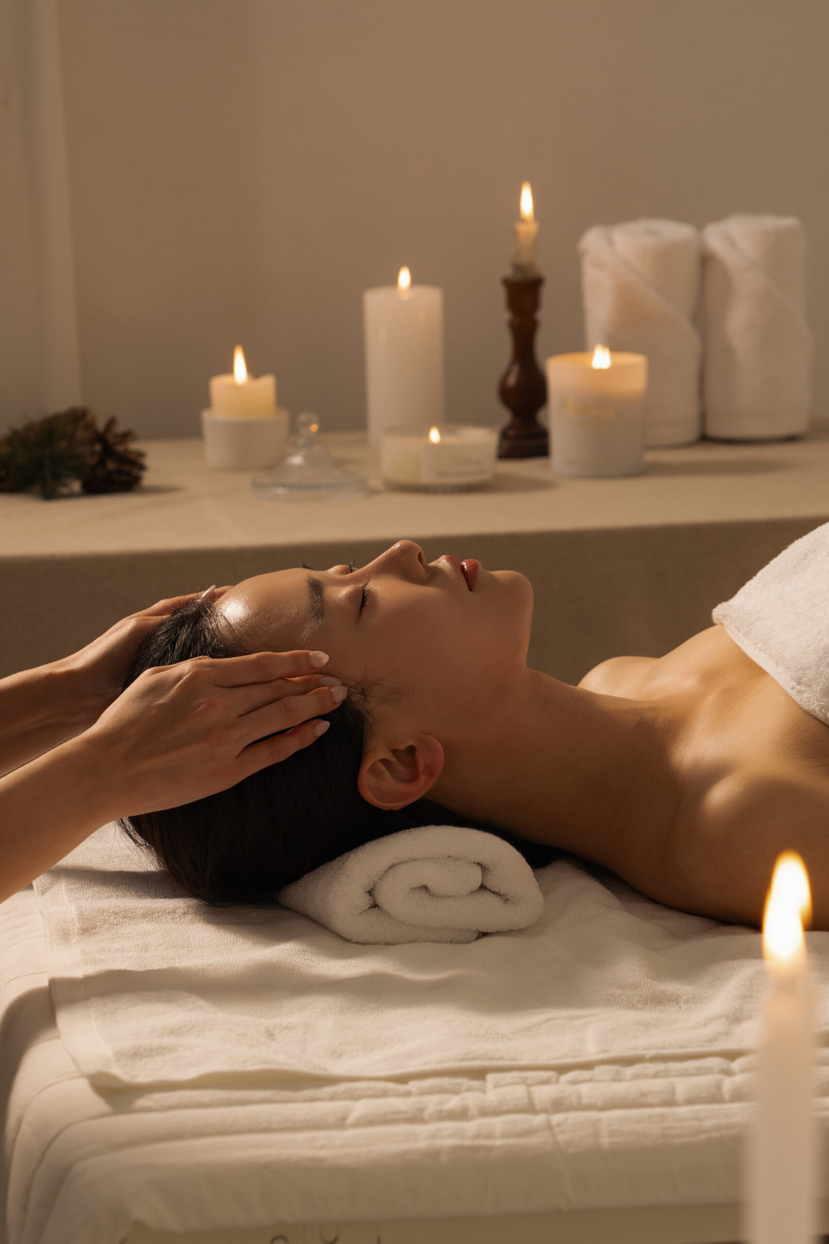 Young woman relaxing at an esthetic salon, candle in the background, gettinga relaxing head massage